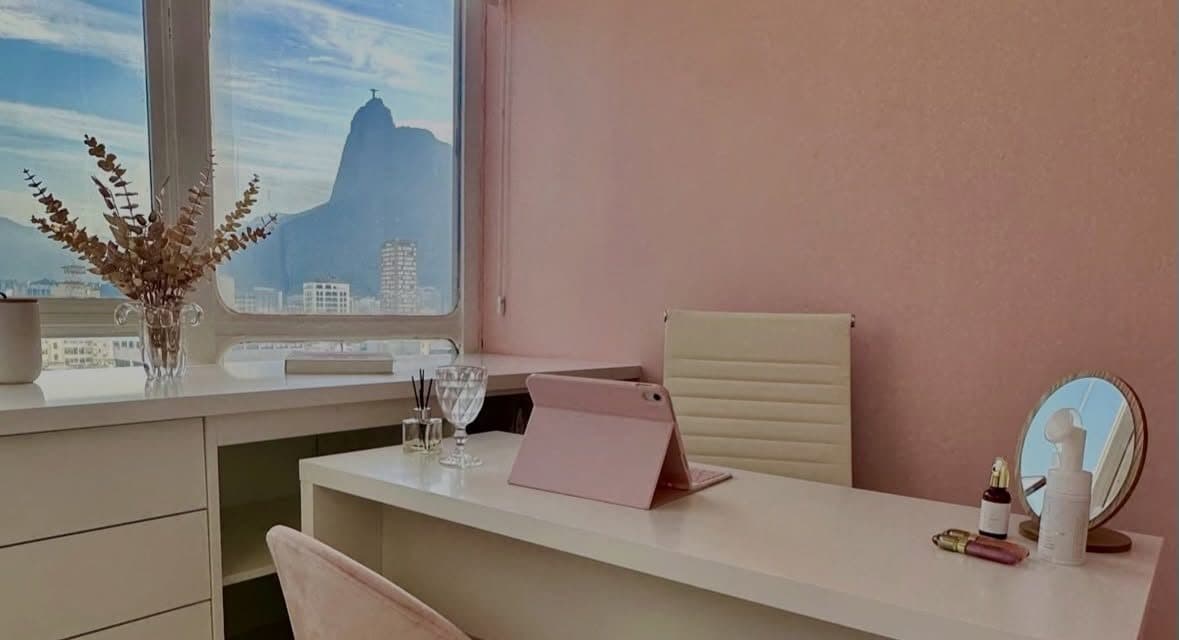 Sala de atendimento da clínica, com paredes rosadas e o Cristo Redentor na janela
